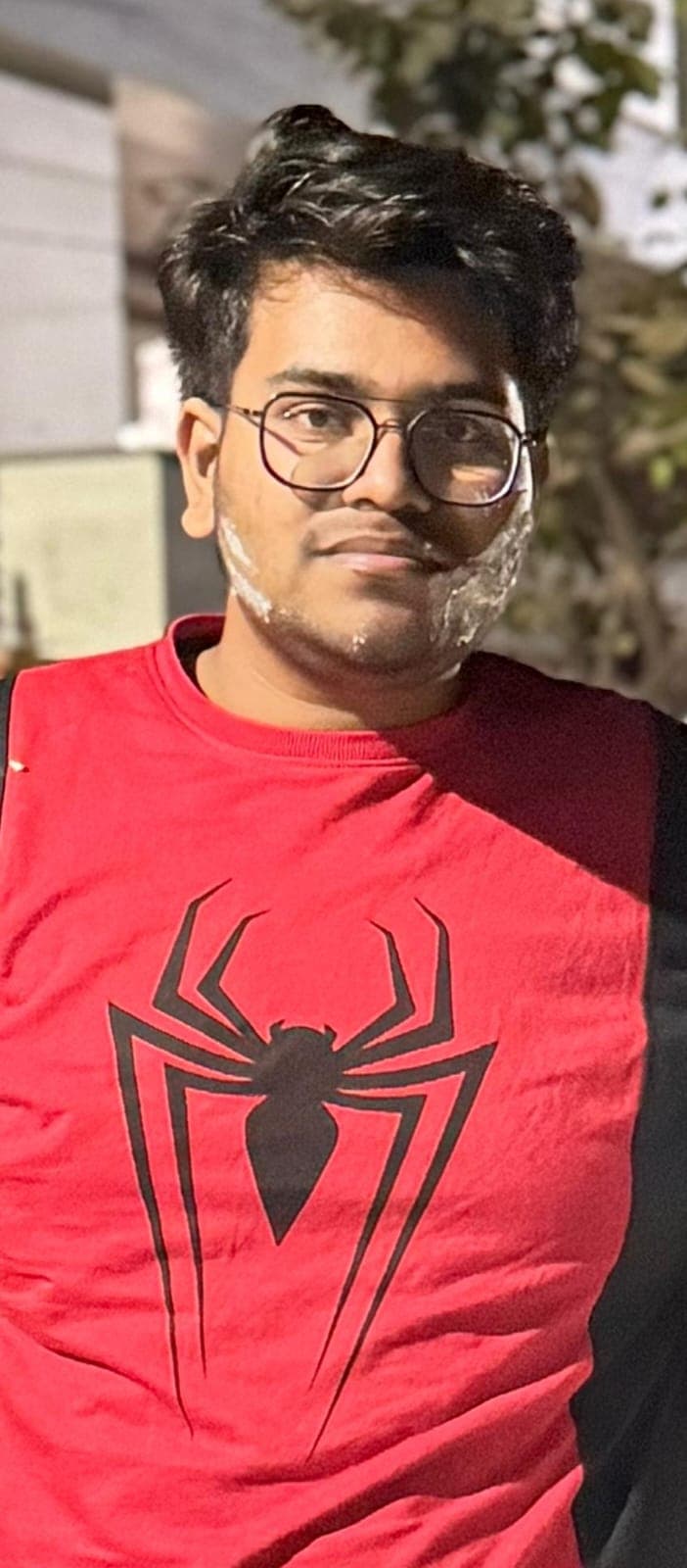Young man wearing a red Spider-Man shirt with white frosting smeared on his face.